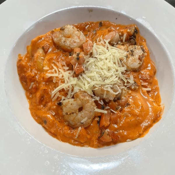 Casa Express's creamy tomato pasta with shrimp and shredded Parmesan cheese in a white bowl.