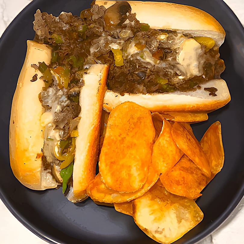 A Casa Express Italian cheesesteak sandwich with peppers and onions, served with potato chips.